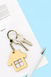Keys and house shaped keychain on real estate mortgage loan document, contract agreement to buy or construction new home, insurance, registration of lease, rent apartments. Vertical blue background