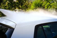 The Roof Of A White Car Is Cleaned With A High-pressure Cleaner.