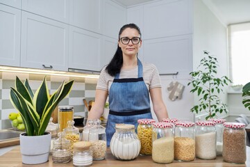 Wall Mural - Portrait of smiling woman housewife in an apron in kitchen