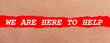 © Елена Дигилевич - A strip of red paper under the torn brown paper. White lettering on red paper WE ARE HERE TO HELP. View from above