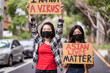 © Juan Alberto Ruiz/ADDICTIVE STOCK - Ethnic females in masks holding posters protesting against racism in city street and looking at camera