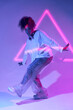 © Manuel Ruiz/ADDICTIVE STOCK - Full body talented young African American female dancer in loose clothes dancing in studio in neon lights and looking at camera