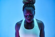 © Manuel Ruiz/ADDICTIVE STOCK - Young African American sportswoman with Afro braids in bun and closed eyes on blue background