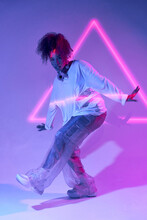 Full Body Talented Young African American Female Dancer In Loose Clothes Dancing In Studio In Neon Lights And Looking At Camera