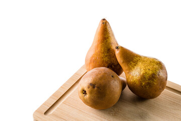 three brown pears on wooden cutting board isolated on white background