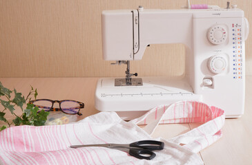 Wall Mural - eco shopping bag made of cotton fabric, sewing machine, scissors, glasses and spools of thread on the table, copy space