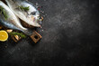© nadianb - Fresh fish dorado on black stone table with ingredients for cooking. Top view with copy space.