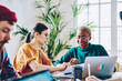 © BullRun - African American and Caucaisan female colleagues analyzing paper report discussing business details during work time for collaborate, diverse students communicate during together studying indoors