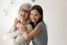Family Portrait Of Happy Mature Old Mother And Adult Teenage Daughter Hug And Cuddle Spend Weekend Time Together. Smiling Middle-aged 60s Mom And Grownup Teen Child Embrace Show Love And Care.