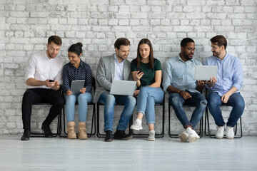 Diverse couples of millennial gadget users sharing content on tablet, smartphone, laptop screens. Group of friends watching and discussing videos together, checking social media news, shopping online