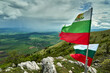 The lush green Kraishte mountain ranges in Bulgaria, Europe, in spring, against a dramatic cloud backdrop, as seen from the Lubash peak slopes. Bulgarian flags on the summit