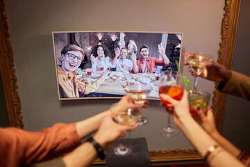 Wall Mural - Close up of unrecognizable group of people clinking glasses to screen while celebrating online with friends