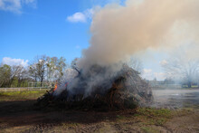 Closeup Of A Pile Of Burning Dried Branches In A Field Under The Sunlight