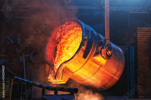 Big ladle container with molten liquid metal or iron in foundry close up.