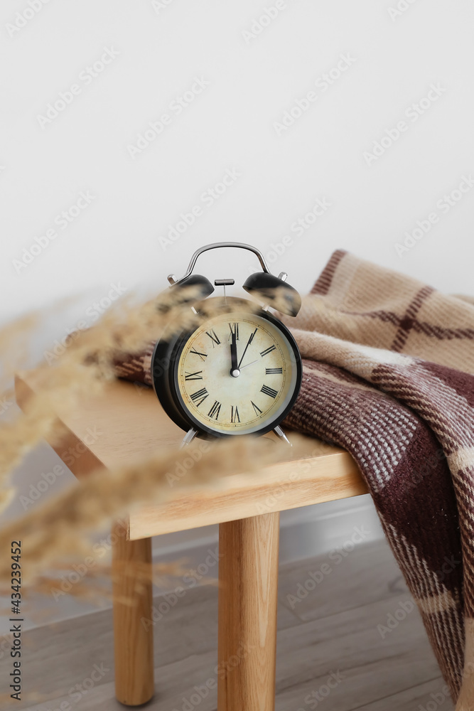 Alarm clock on wooden table near white wall