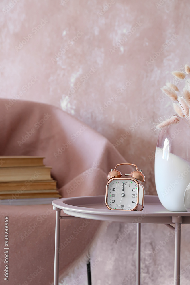 Alarm clock on table near color wall