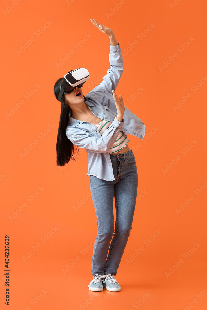 Young woman with VR glasses on color background
