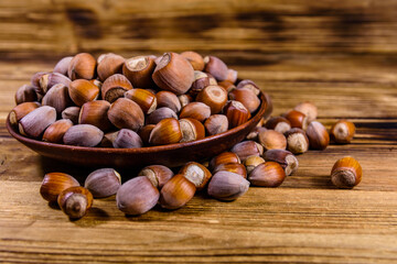Canvas Print - Plate with pile of hazelnuts on a wooden table