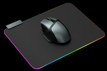 Modern gaming computer mouse on professional pad on black background