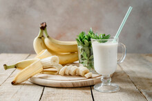 Yogurt Banana Shake In A Latte Coffee Glass With Handle With Mint Leaves And Bananas With Handle On Wooden Background