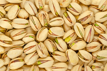 Wall Mural - Roasted and salted pistachio seeds with shell, background, from above. Snack food, made from fruits of Pistacia vera. Green kernels in light yellow shells, ready to eat. Backdrop. Macro food photo.