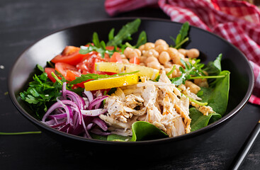 Buddha bowl dish with chicken fillet, chickpeas, tomatoes, red onion, fresh green salad and seed sesame. Healthy balanced eating.