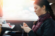 A young caucasian woman sits in a car and cross-stitching. Side view. Copy space