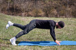 © Igor Syrbu - Playful sportsman extends leg behind him on fitness mat in the park