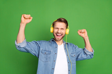 Sticker - Photo portrait of young guy listening music wearing headphones dancing relaxing at party isolated vibrant green color background