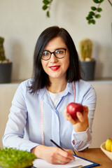 Nutritionist, dietitian woman at the office, hold apple in the hand