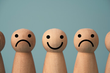 Wall Mural - Wooden figure smile between sadness on blue background , Emotion selection and lifestyle concept.