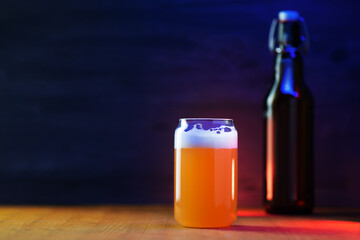 Wall Mural - Stylish creative glass of unfiltered wheat beer, beer bottle with a hook cap. Black copy space background. Color blue backlight. Menu