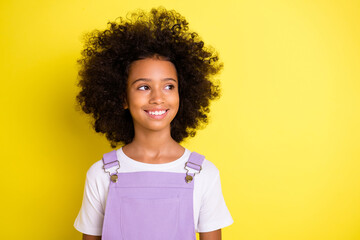 Wall Mural - Portrait of optimistic cute curly girl wear white t-shirt look empty space isolated on yellow color background