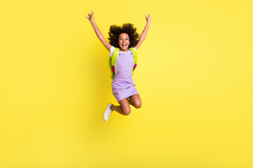 Poster - Full length body size photo of funny schoolgirl jumping high with rucksack laughing careless isolated vivid yellow color background