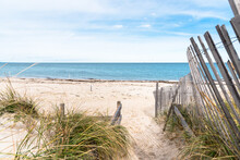 Path Lined With A Weathered Fence Through Sand Dunes To A Beautiful Deserted Sandy Beach On A Partly Cloudy Autumn Day. Cape Cod, MA, USA.