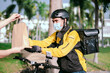 © 2B - Courier wearing a yellow company shirt, riding a bicycle, delivering food paper bags to customers