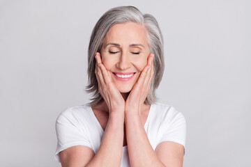 Photo of pretty charming age woman dressed white outfit smiling closed eyes arms cheeks isolated grey color background