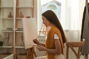 Poster - Beautiful young woman drawing on easel at home