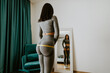 © shevtsovy - attractive slim Woman Measuring body With Tape Standing In Front Of Mirror At Home. Beautiful woman checking success of weight loss program and measuring butt and hips in front of mirror in living
