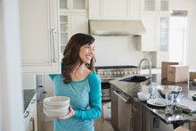 Woman Putting Away Dishes In New Home