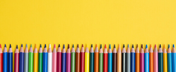 Coloring pencils isolated on yellow background close up concept with copy space for text 