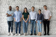 © fizkes - Group portrait of diverse millennial team of employees, company workforce, department staff. Happy multiethnic business people standing in row against wall, looking at camera, smiling. Full length