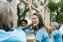 Cheerful Teenage Girl Working With Volunteers At Construction Site