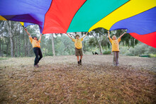 Children Playing With Colorful Parachute In Forest