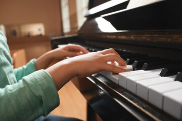 little child playing piano indoors, closeup. music lesson