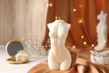 Composition with beautiful female body shaped candle on white table
