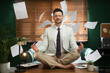 © New Africa - Calm businessman meditating on office desk in middle of busy work day