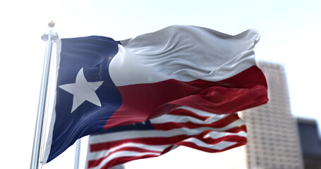 The Texas state flag flapping in the wind with the American national flag blurred in the background