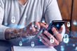© VideoFlow - A programmer is browsing the Internet in smart phone to protect a cyber security from hacker attacks and save clients confidential data. Padlock Hologram icons over the typing hands.