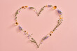 Heart shape with copy space on pink pastel background, with bottles of essential oil, frankincense, lavender and thyme